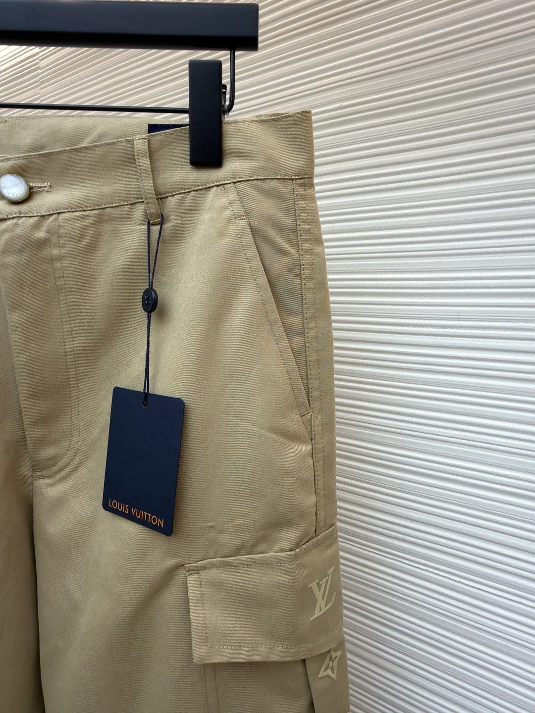 LOUIS VUITTON pocket embroidered work trousers ●Original version: Purchased and developed by 11318 ●Item number: 1681826-B50 ●Fabric: cotton twill fabric ●Technology: embroidery production ●Color: Khaki ●Version: Fitted version ●Weight: about 505 grams ●Size: 44-46-48-50 ●Description: The high cotton content ensures the fabric's excellent breathability, durability and classic workwear texture, while the twill weave gives it unique wear resistance and stiffness. The special fabric technology solves the pain points of tight and stiff traditional overalls; it provides greater freedom when moving, significantly improves wearing comfort and flexibility, and achieves a balance between function and comfort. The application of three-dimensional core-spinning embroidery technology in the pocket position is achieved by adding additional cotton thread or foam as the core material to the pattern filling layer, and then using embroidery thread to fully cover the embroidery. The logo pattern is significantly protruded from the surface of the fabric, forming a full three-dimensional effect. This process not only enhances the visual impact and tactile level, but also improves the wear resistance of the pocket area through the buffering effect of the core material, ensuring that the pattern can still remain crisp and not deformed in complex daily use, ensuring that the pattern is clear and durable, and injecting a sense of sophistication into the rugged workwear style. Diversified pocket system combines workwear functionality with sophistication. The flap cargo pockets on both sides are a signature element, and their flap design prevents items from falling and enhances the visual three-dimensionality. Italian style pockets provide simple side storage. The overall wiring is straight and delicate, the fabric is comfortable and soft, and the color is consistent without color difference. It can be matched with the same style to create a fashionable look and control various occasions. Customized accessories, complete with three standards, same style for men and women!